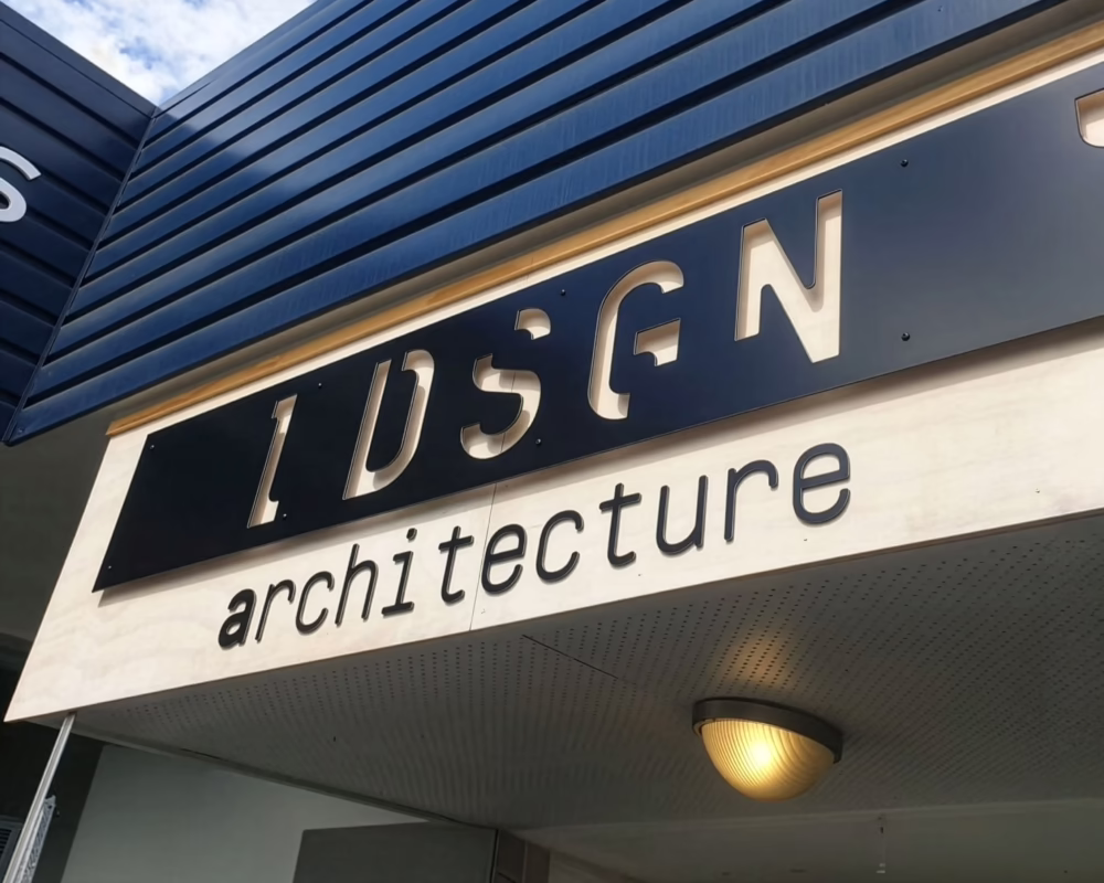 Custom exterior fascia sign for IDSGN architecture in Timaru featuring 3D cut-out metallic lettering on a black panel.