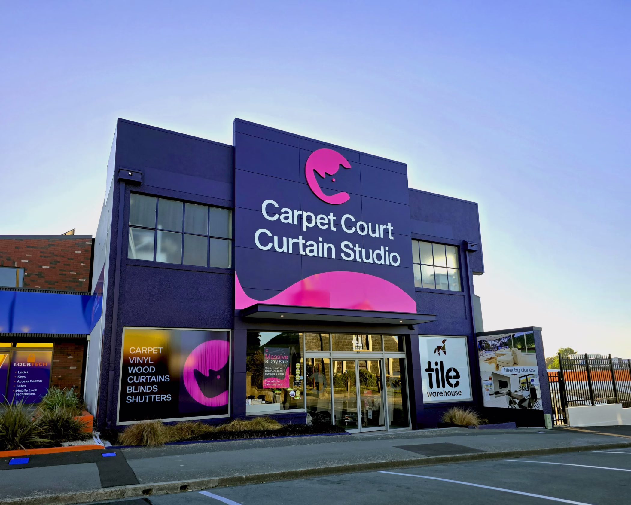 Exterior building fascia sign and window graphics for Carpet Court Curtain Studio, Timaru, featuring purple and pink colors and custom logo branding.
