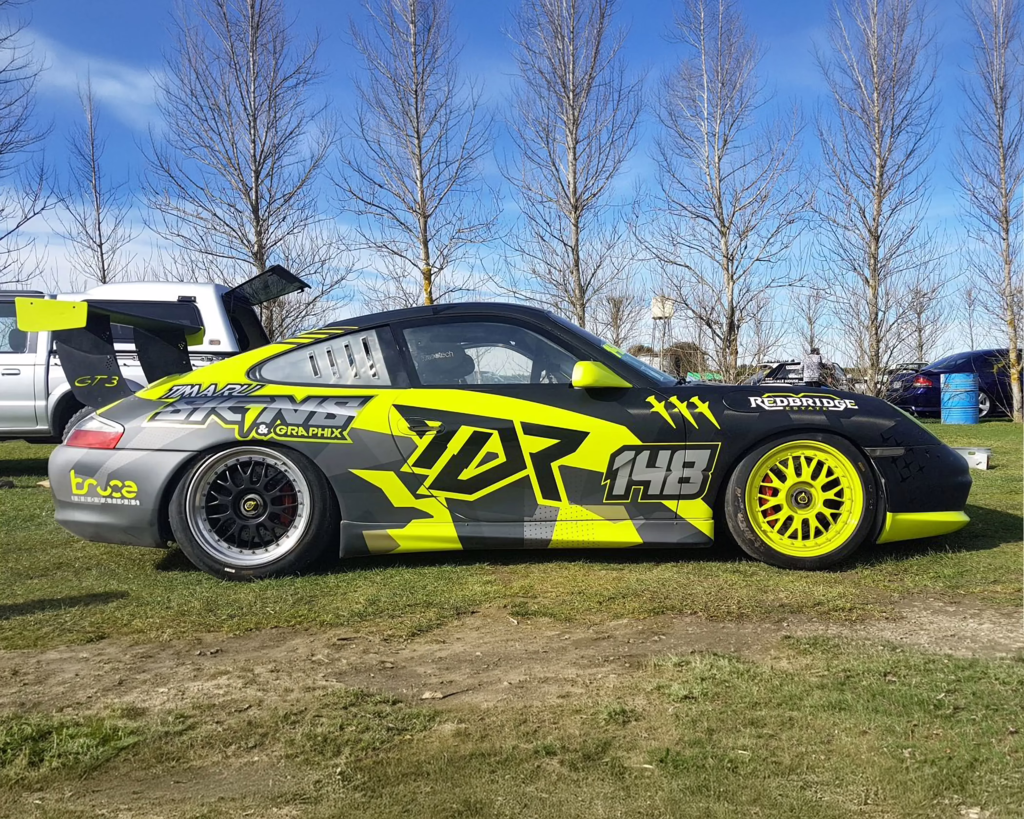 Custom neon yellow and black motorsport graphic wrap for a TDR Porsche 996 GT3 race car.