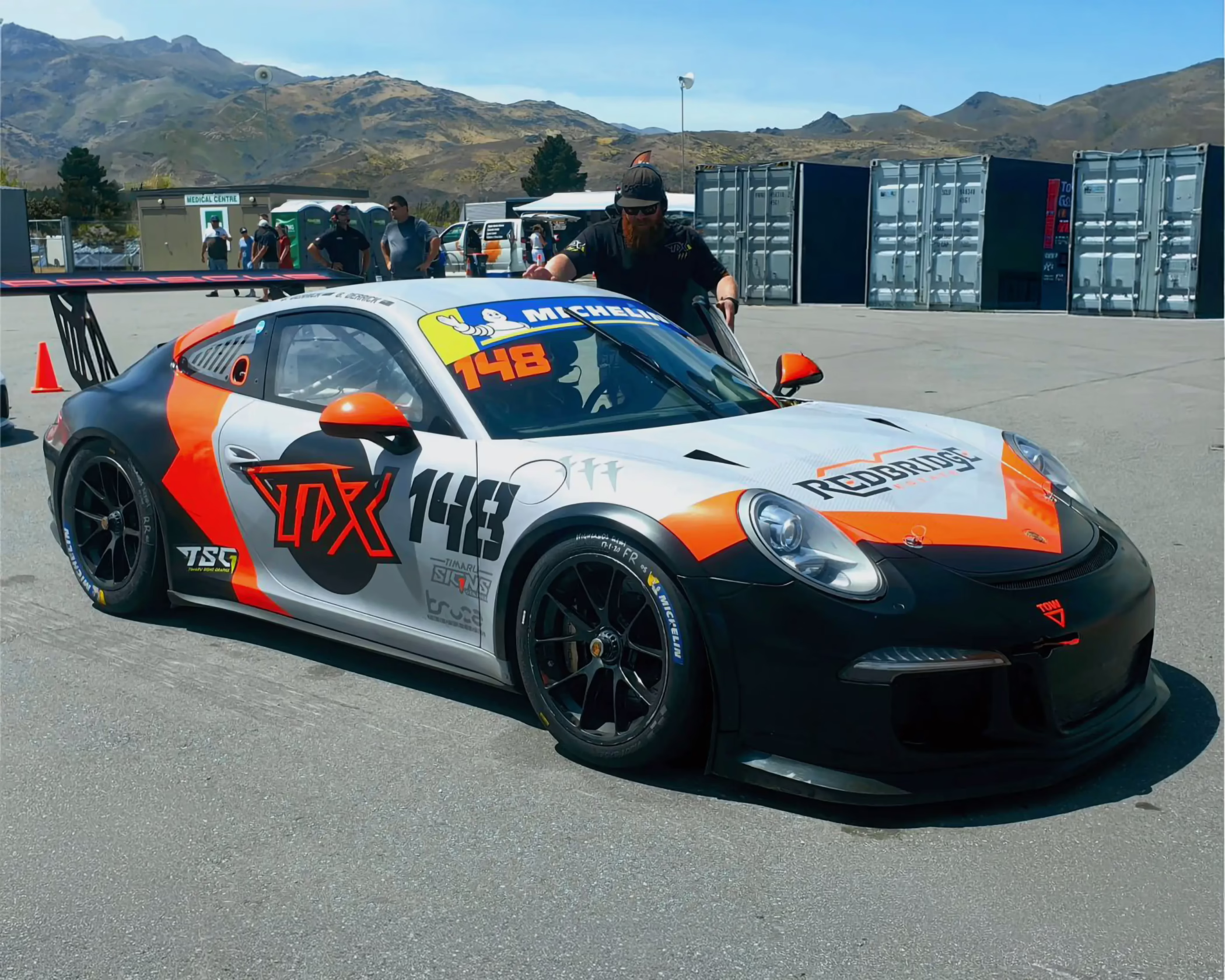 Custom orange, black, and white race car livery wrap on TDX 148 Porsche by Timaru Signs Graphix.