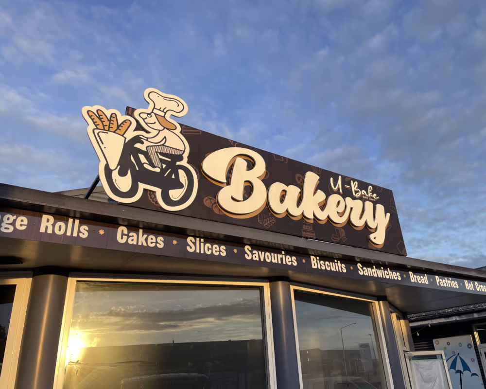 Custom exterior building fascia sign for U-Bake Bakery in Timaru, featuring brown and cream shopfront graphics.
