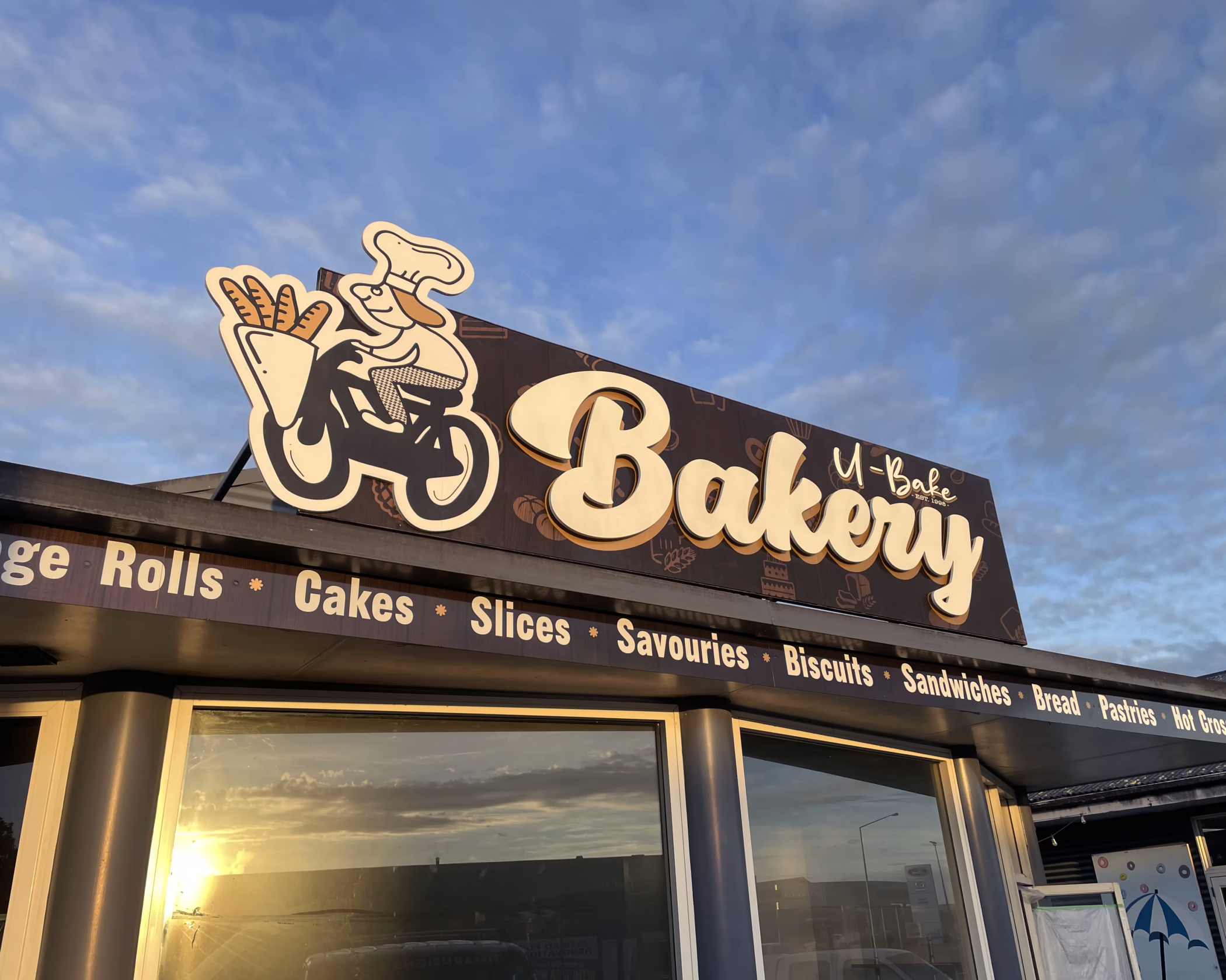 Custom exterior building fascia sign for U-Bake Bakery in Timaru, featuring brown and cream shopfront graphics.
