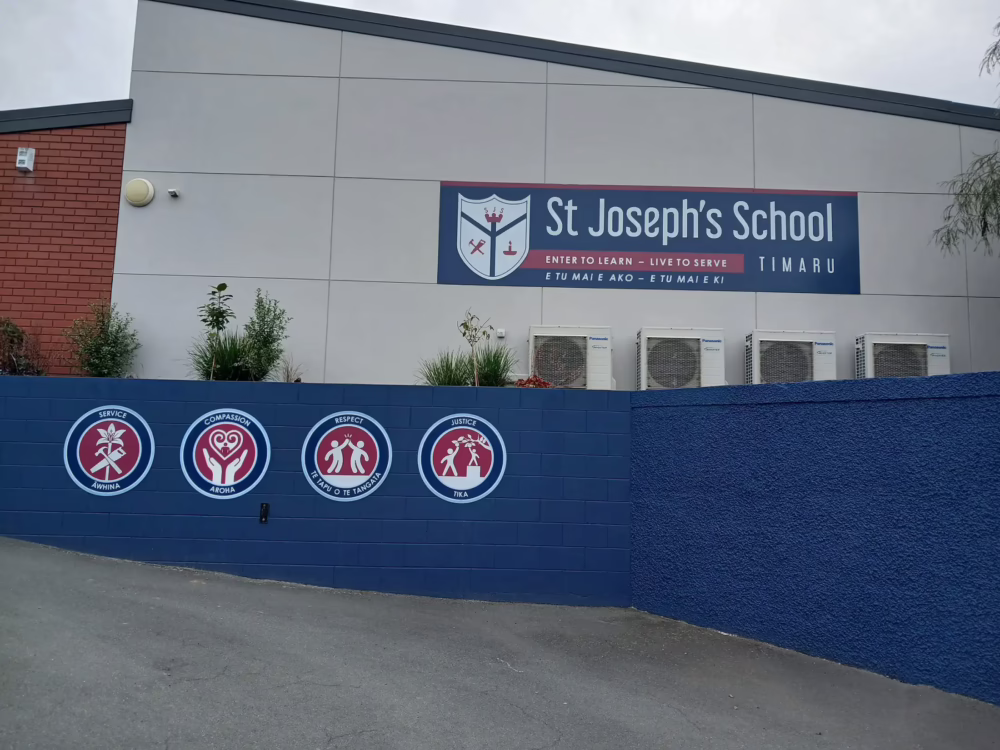 St Joseph's School Timaru exterior building signage with custom core value emblems on blue retaining wall and main fascia banner.