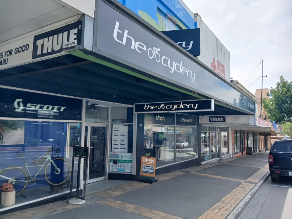 Custom grey and white exterior building fascia sign and shopfront graphics for The Cyclery in Timaru.