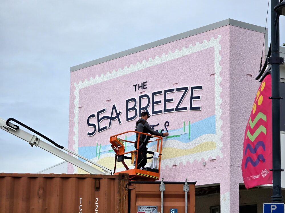Custom pink postage stamp exterior building fascia sign for The Sea Breeze, being installed by Timaru Signs Graphix.