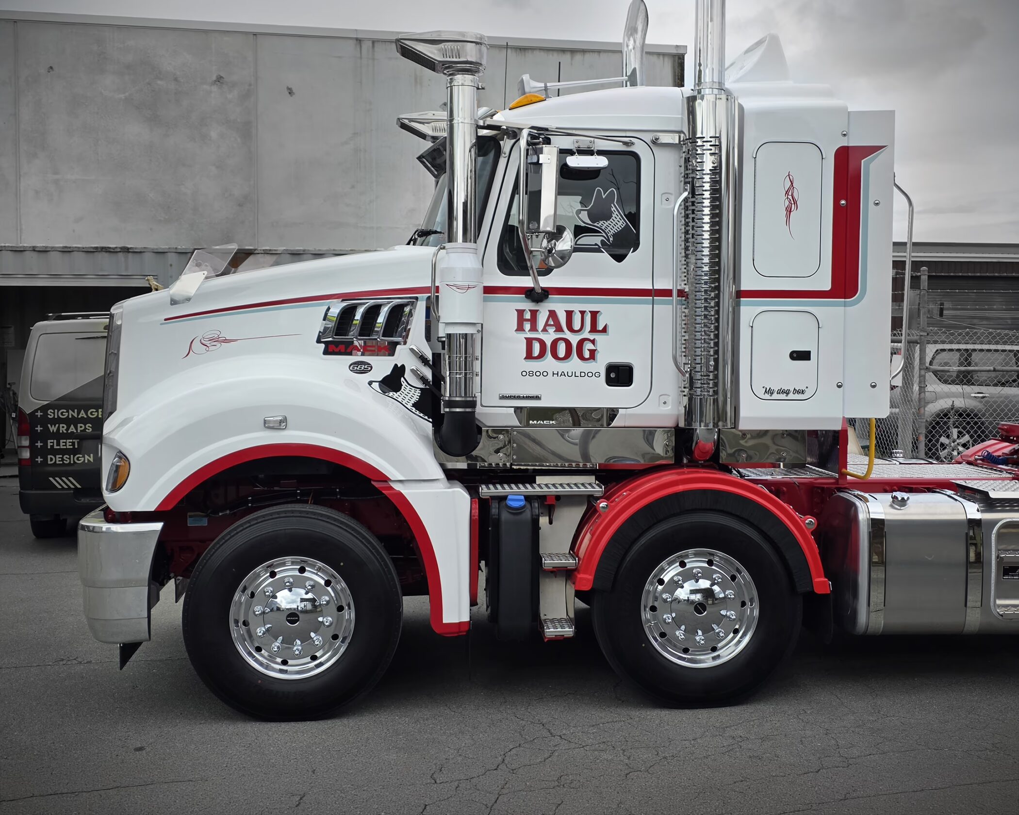 Side view of a custom white and red Mack truck with "HAUL DOG" branding and chrome details.