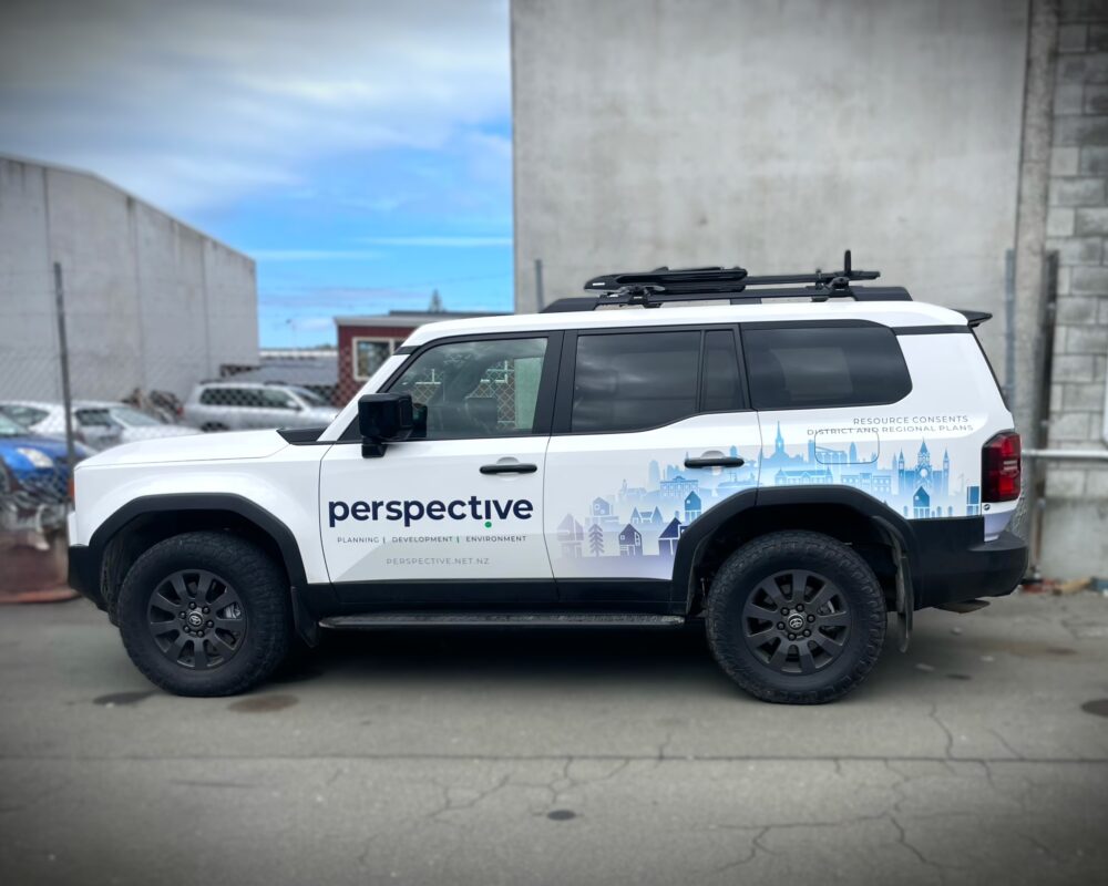 Side view of a white Toyota Land Cruiser Prado branded with "Perspective" graphics and logos.