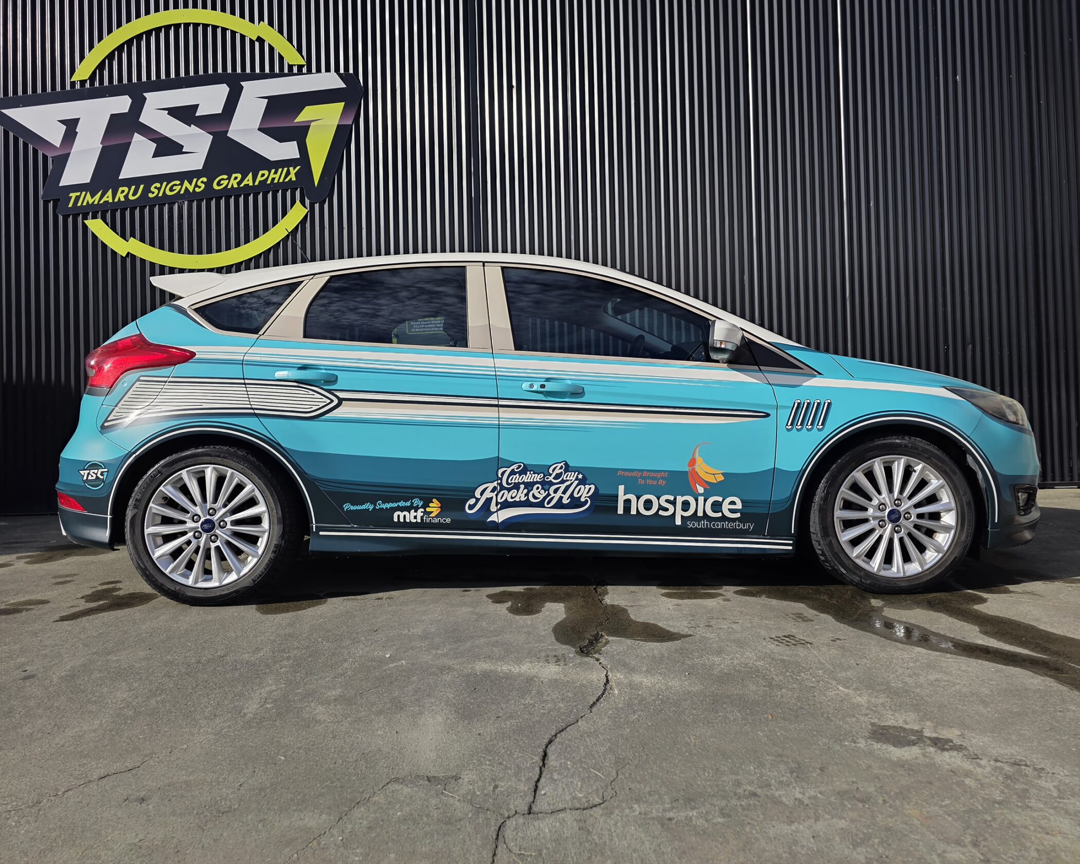 Custom full commercial vehicle wrap in blue and white, featuring Caroline Bay Rock & Hop and Hospice logos by Timaru Signs Graphix.