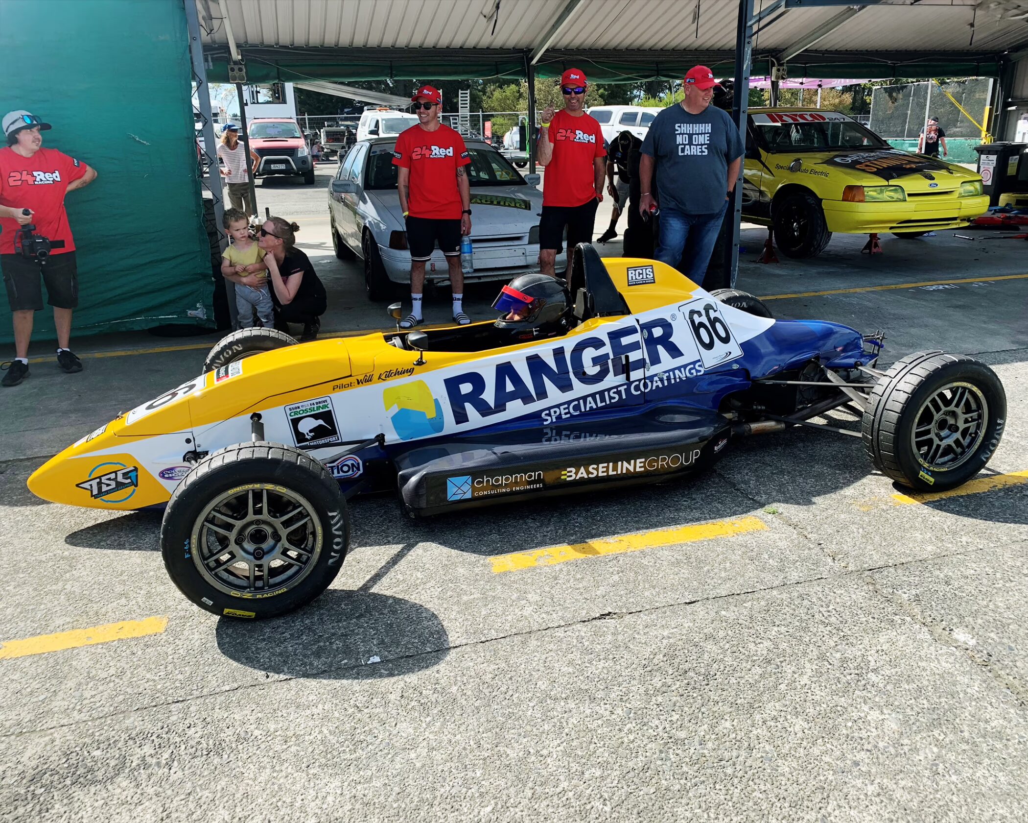 Open-wheel Formula Ford race car with custom vehicle graphics created for pilot Will Kitching. The livery features a vibrant yellow, navy blue, and white design with prominent "RANGER SPECIALIST COATINGS" and "TSG" sponsor branding along the side panels.