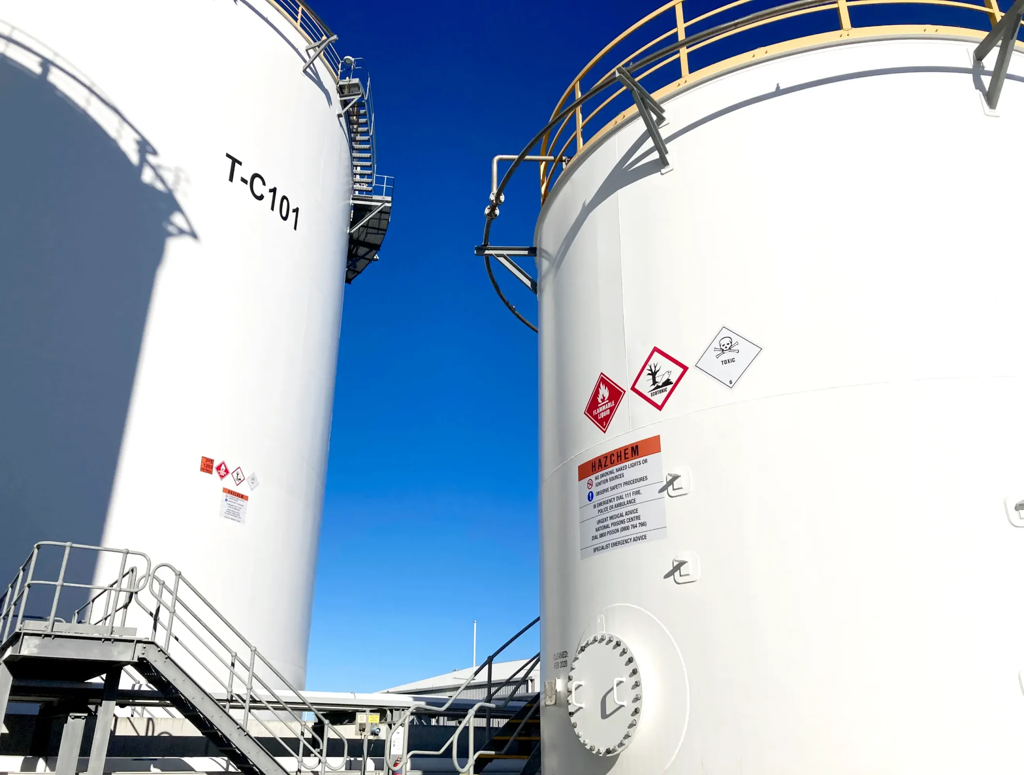 Custom HAZCHEM safety signage and GHS decals on white bulk fuel storage tanks by Timaru Signs Graphix.